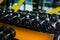 A full set of fixed-weight dumbbells, equipment for weight workout, routine on a dark blurred background.