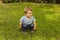 Full shot portrait cute smiley baby boy squat in the grass