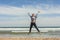 Full shot of a smily teenager jumping in the seashore of the beach in a clear day. Easter.
