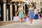 Full side photo of cheerful people with brunette hair red lips stick holding bags moving in town