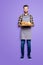 Full size body portrait of joyful cheerful baker in jeans, shoes, shirt, apron with stubble having, showing tray with