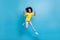 Full size photo of afro american trendy brunette little girl jump win wear yellow t-shirt jeans isolated on blue color