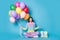 Full size photo of astonished girl sit confetti fall hold balloons giftbox wear trousers jumper isolated blue color