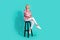 Full size photo of attractive young woman sit chair elegant relaxed wear trendy pink print clothes  on cyan