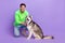 Full size photo of cheerful funny satisfied guy dressed green hoodie jeans petting his dog husky isolated on violet