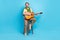 Full size photo of cheerful musician sitting chair playing singing isolated on bright blue color background