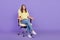 Full size photo of curious millennial brunette hr lady sit on armchair look wear top jeans shoes isolated on violet