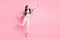 Full size photo of dreamy charming little girl reach out hand empty space look imagine isolated on pink color background