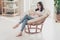 Full size photo of focused girl sit wicker chair comment post on cellphone in house indoors wear casual style clothes