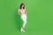 Full size photo of gorgeous fancy girl with curly hairdo wear blouse white trousers hands in pockets isolated on green