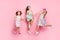 Full size photo of lovely siblings jumping wearing bright skirt dress headband isolated over pink background