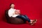 Full size photo of mature excited good mood man sit armchair watch 3d film eat pop corn isolated on red color background