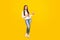 Full size photo of nice brunette teen girl index empty space wear white sweater jeans shoes isolated on yellow color