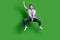 Full size photo of optimistic funky guy jump horse wear blue shirt jeans footwear isolated on green color background