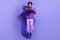 Full size photo of optimistic funny person dressed violet hoodie pants holding steering wheel jumping isolated on purple