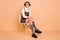 Full size photo of optimistic short hairdo girl sit wear dress socks shoes isolated on peach color background