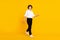 Full size photo of optimistic small brunet boy go wear white shirt trousers shoes isolated on yellow background