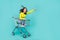 Full size photo of overjoyed carefree girl sit inside market trolley ride empty space isolated on teal color background