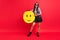 Full size photo of positive cheerful young woman hold paper pinata smile emoji good mood isolated on red color