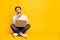 Full size photo of serious minded man sit floor hold laptop look empty space  on yellow color background