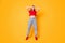 Full size photo of shocked lady hands on head stand on toes wear red crop top jeans shoes isolated on yellow color