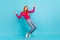 Full size photo of young joyful ginger head lady dance wear pink sweater jeans  on vivid blue color background