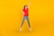 Full size photo of young pretty girl energetic jump demonstrate arm huge size isolated over yellow color background