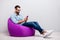 Full size profile photo of crazy guy sitting comfy soft violet armchair holding telephone chatting colleagues wear specs