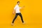 Full size profile photo of funky brunet young guy run wear shirt jeans sneakers isolated on yellow color background