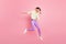 Full size profile photo of optimistic brunette lady jump dance dab wear shirt trousers sneakers isolated on pastel pink