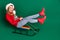 Full size profile photo of optimistic santa young lady slide on sled wear sweater jeans boots isolated on green