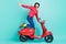 Full size profile side photo of funky smiling extreme young man riding moped fast speed isolated on teal color