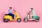 Full size profile side photo of shocked mature married couple riding driving moped scooter isolated on pink color