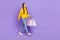 Full size profile side picture of walking female shopaholic dreaming wear denim isolated on violet color background