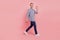 Full size profile side portrait of young handsome guy go walk step happy positive smile waving hello isolated over pink