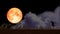 Full strawberry blood moon back on night sky and blur cloud moving pass on roof