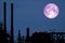 Full Strawberry Moon back on silhouette refinery on night sky