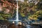 Full view of the red cliffs, plunge pool, and moss and fern cove