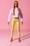 Full view of stylish, blonde african american woman standing on pink background, fashion doll concept