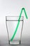 A full water glass with a green drinking straw