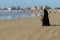 A fully covered Muslim woman walking with her little son on the beach