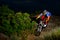 Fully Equipped Professional Downhill Cyclist Riding the Bike on the Night Rocky Trail