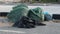 Fully filled green plastic trash bins spilled on the street. Waste and recycle concept. Slow motion