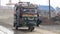 A fully loaded three wheeler auto rickshaw tempo carrying rural passengers on the road.