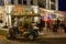 Fully occupied tables and chairs at a restaurant in evening. In the foreground you can see a golf cart for bringing guests to thei