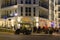 Fully occupied tables and chairs at a restaurant in evening. In the foreground you can see a golf cart for bringing guests to thei