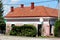 Fully renovated small suburban family house with new facade and roof tiles surrounded with garden plants and electrical wires