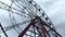 A fun attraction. Large Ferris wheel close-up against a gray cloudy sky.