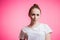 A fun cunning student girl slyly smiling at camera on a pink background