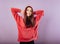 Fun enjoying toothy smiling sporty woman posing in fashion red hoodie on purple bright background with empty copy space. Happy